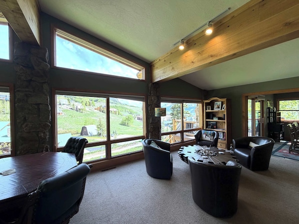 A spacious room with large windows, a wooden ceiling, and a stone wall. - King Davis House-Best Views in Mt. Crested Butte (Crested Butte)