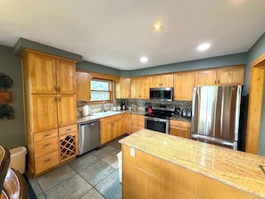 A kitchen with wooden cabinets, stainless steel appliances, and a granite countertop. - King Davis House-Best Views in Mt. Crested Butte (Crested Butte)