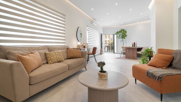 Un salon moderne comprenant un canapé, un fauteuil, une table basse et un coin repas avec une table et des chaises.