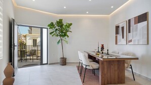 Un espace repas moderne avec une table en bois, des chaises, une plante en pot et des œuvres d’art accrochées au mur.