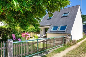 Ein Haus mit geneigtem Dach, einem umzäunten Hinterhof und einem Weg, der zur Eingangstür führt.