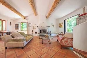 Een woonkamer met een open haard, twee banken, een salontafel en een eethoek met een tafel en stoelen.