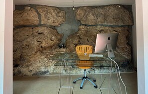 Een moderne werkplek met een glazen bureau, een Apple iMac en een houten stoel.