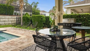 A patio with a pool, outdoor seating, and a grill. - 6BR Disney Escape Pool, SPA and fun (Kissimmee)