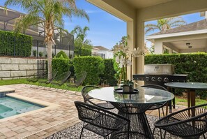 A patio with a pool, outdoor seating, and a grill. - 6BR Disney Escape Pool, SPA and fun (Kissimmee)