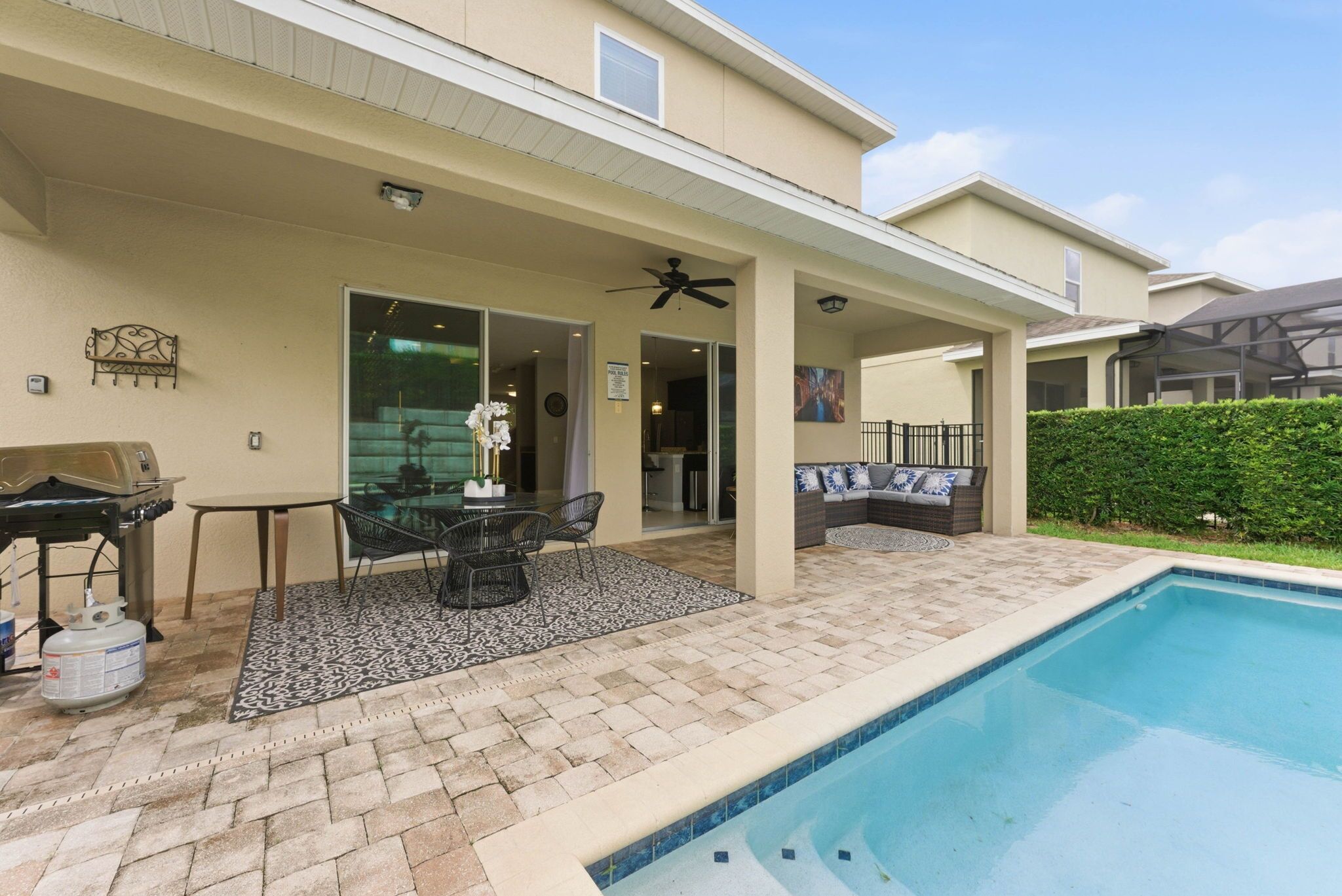 A covered patio area with a pool, outdoor furniture, and a grill.