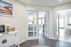 A hallway with a white console, a framed picture, and a vintage radio. - Beach Sunset – Oceanfront Apartment with Terrace and Sea View (Vila Nova de Gaia)