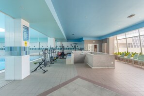 A modern fitness center with exercise equipment, a pool, and a seating area with plants. - Beach Sunset – Oceanfront Apartment with Terrace and Sea View (Vila Nova de Gaia)