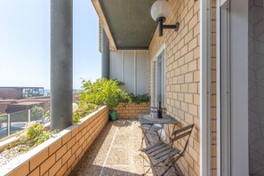 A balcony with a table, chairs, a potted plant, and a bottle of wine. - Beach Sunset – Oceanfront Apartment with Terrace and Sea View (Vila Nova de Gaia)