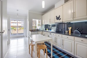 A kitchen with white cabinets, a black countertop, and a blue and black checkered floor. - Beach Sunset – Oceanfront Apartment with Terrace and Sea View (Vila Nova de Gaia)