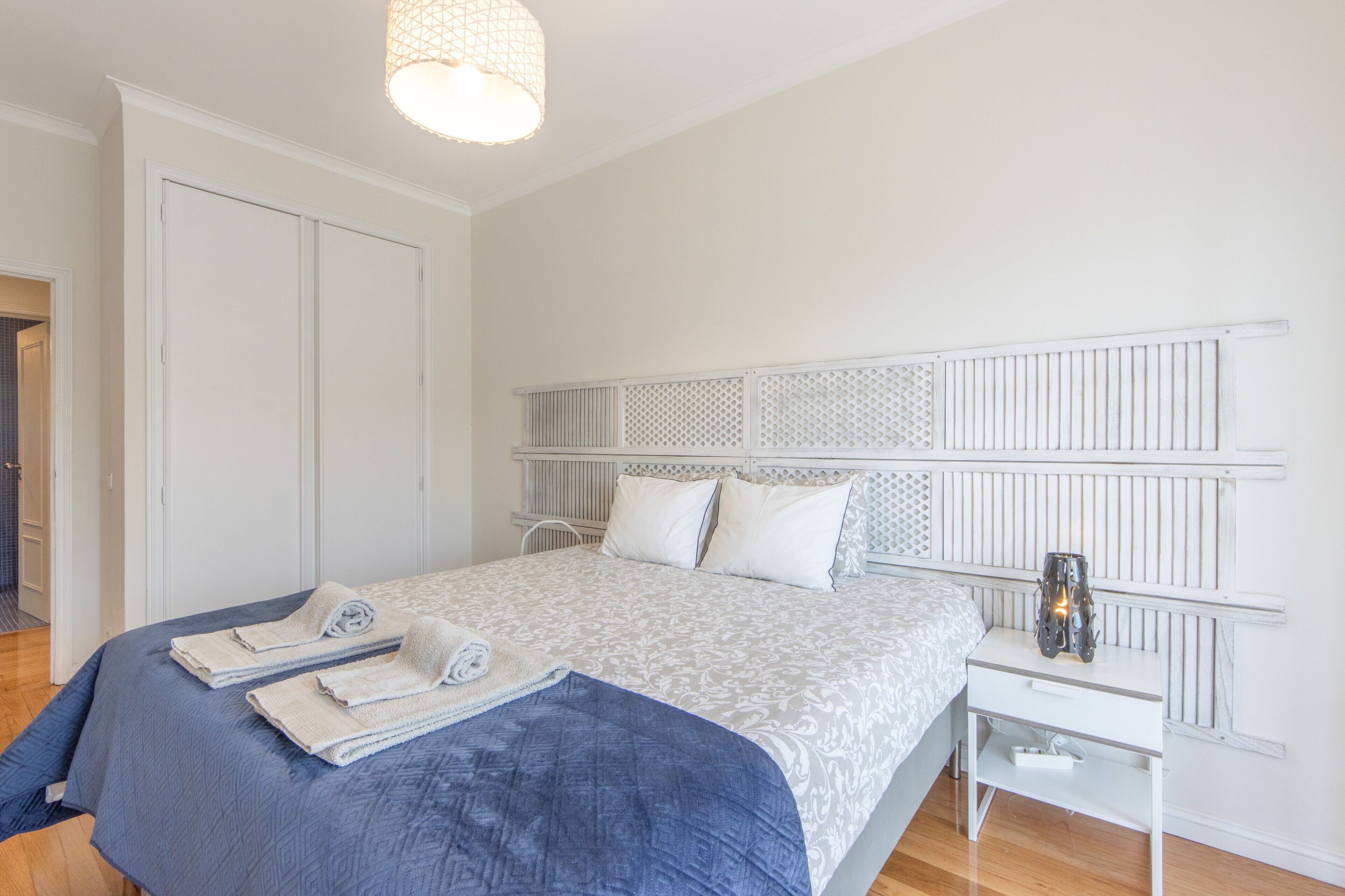 A bedroom with a bed, bedside table, and a hanging light fixture.