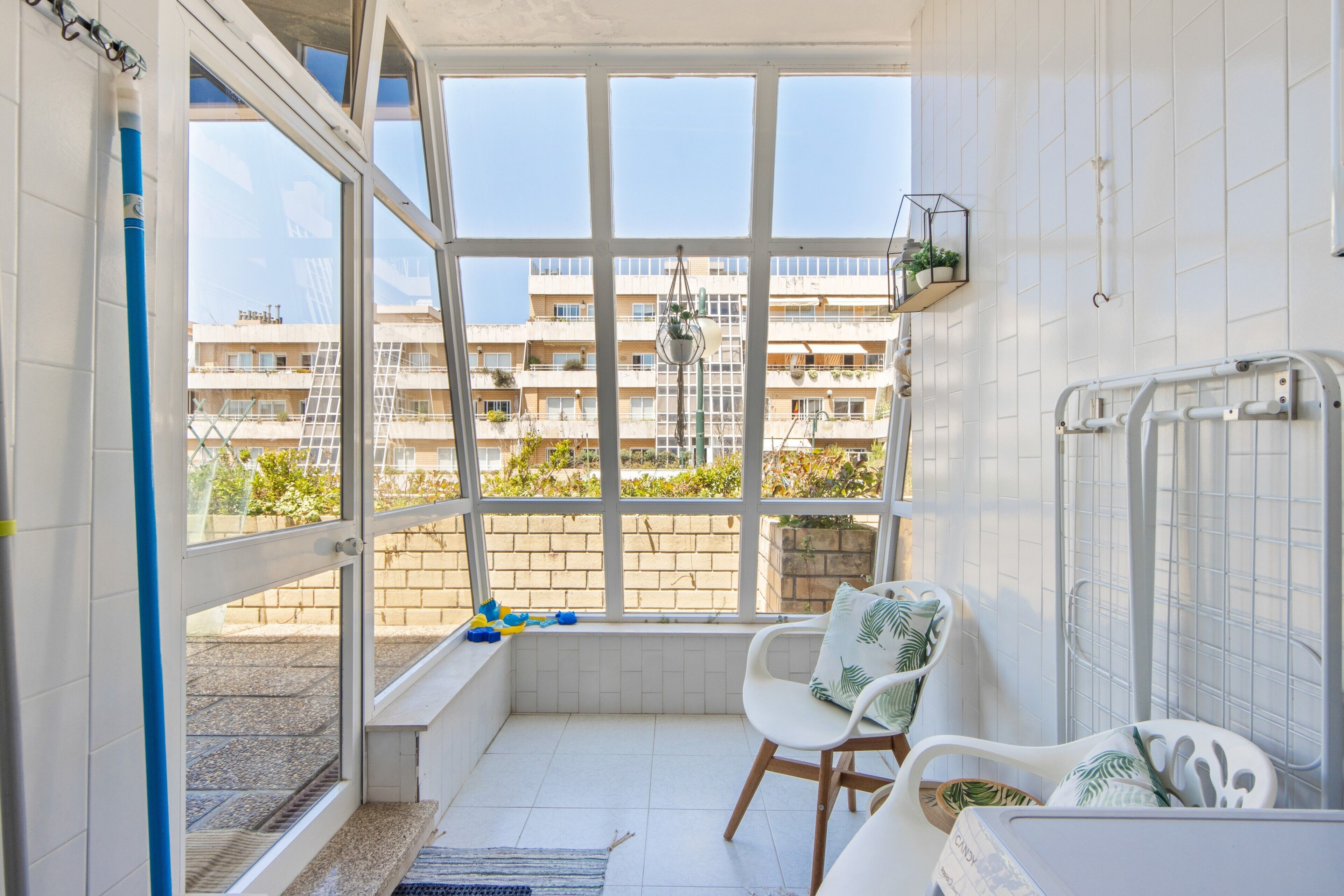 Un balcon donnant sur un immeuble, une chaise, une petite table et un radiateur.