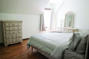 Ein Schlafzimmer mit Bett, Kommode und Spiegel.