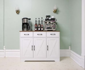 A kitchen with a white cabinet, a coffee maker, and condiment bottles.