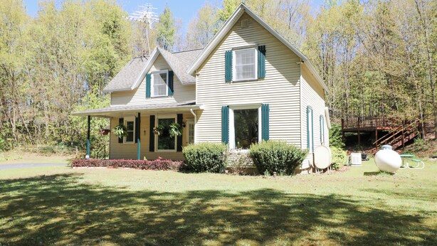 A two-story house with a porch, a chimney, and a deck. - Country Oasis 4-bedroom farmhouse in tranquil Shelby with cozy charm (Shelby)