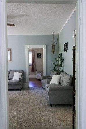 Ein Wohnzimmer mit zwei grauen Sofas, einem kleinen Baum und einer hängenden Laterne.