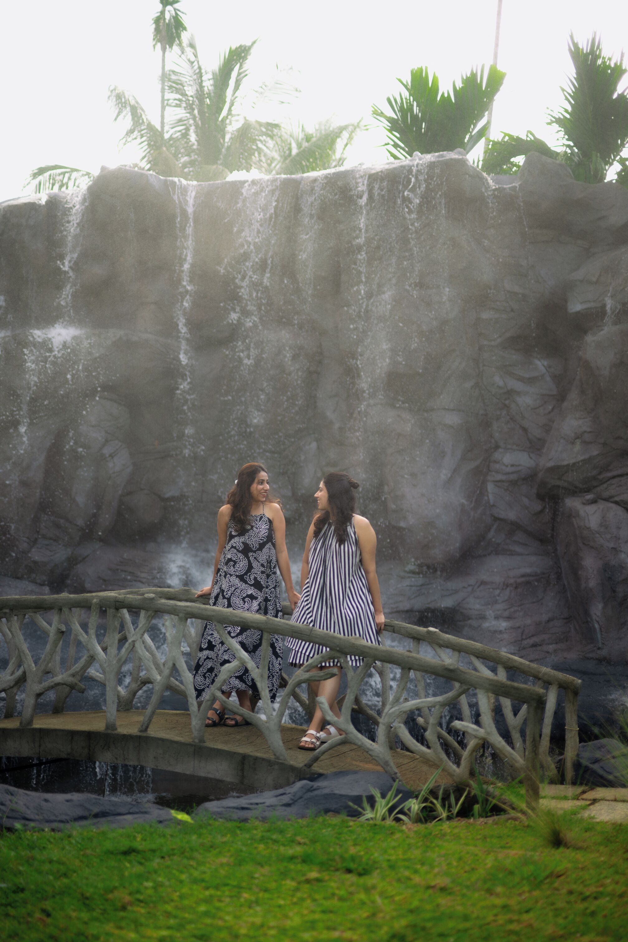 Deux femmes se tiennent sur un pont, avec une cascade en arrière-plan.