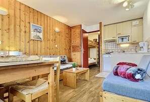 A wooden-paneled room with a dining table, chairs, a sofa, and a kitchenette. - 200m from ski slopes, 5th floor, balcony, tv, 24m², Tignes (Tignes)