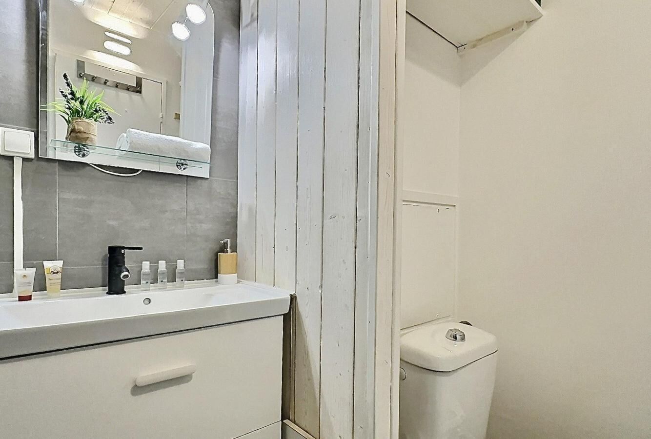 A bathroom with a white sink, mirror, and toilet.