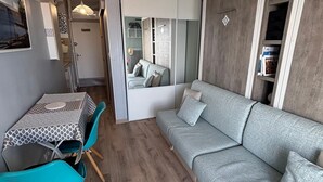 A compact living space with a sofa, a dining table with chairs, and a mirrored closet. - Mini-studio with AC, pond view - 2 guests (Balaruc-les-Bains)