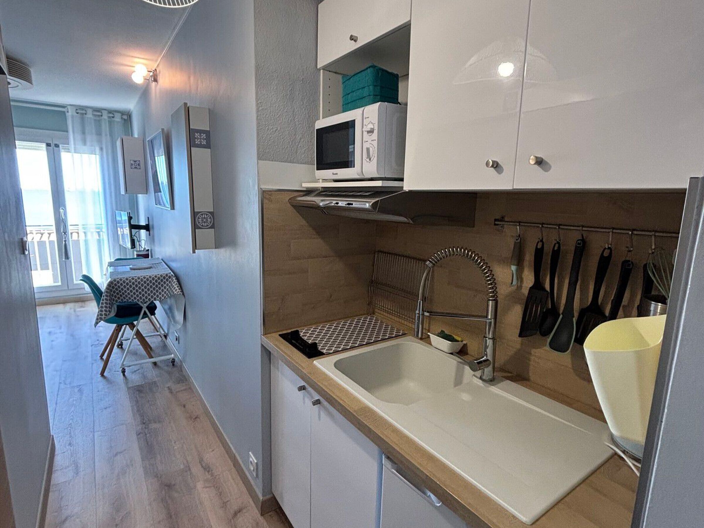 A compact kitchen with a sink, microwave, and cabinets.