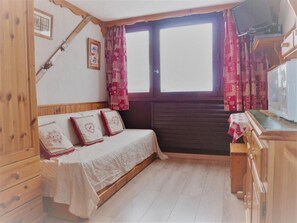 A bedroom with a wooden bed, a wooden wardrobe, a window with curtains, and a television on a wooden stand. - 150m from ski slopes, 3rd floor, tv, 16m², Tignes (Tignes)