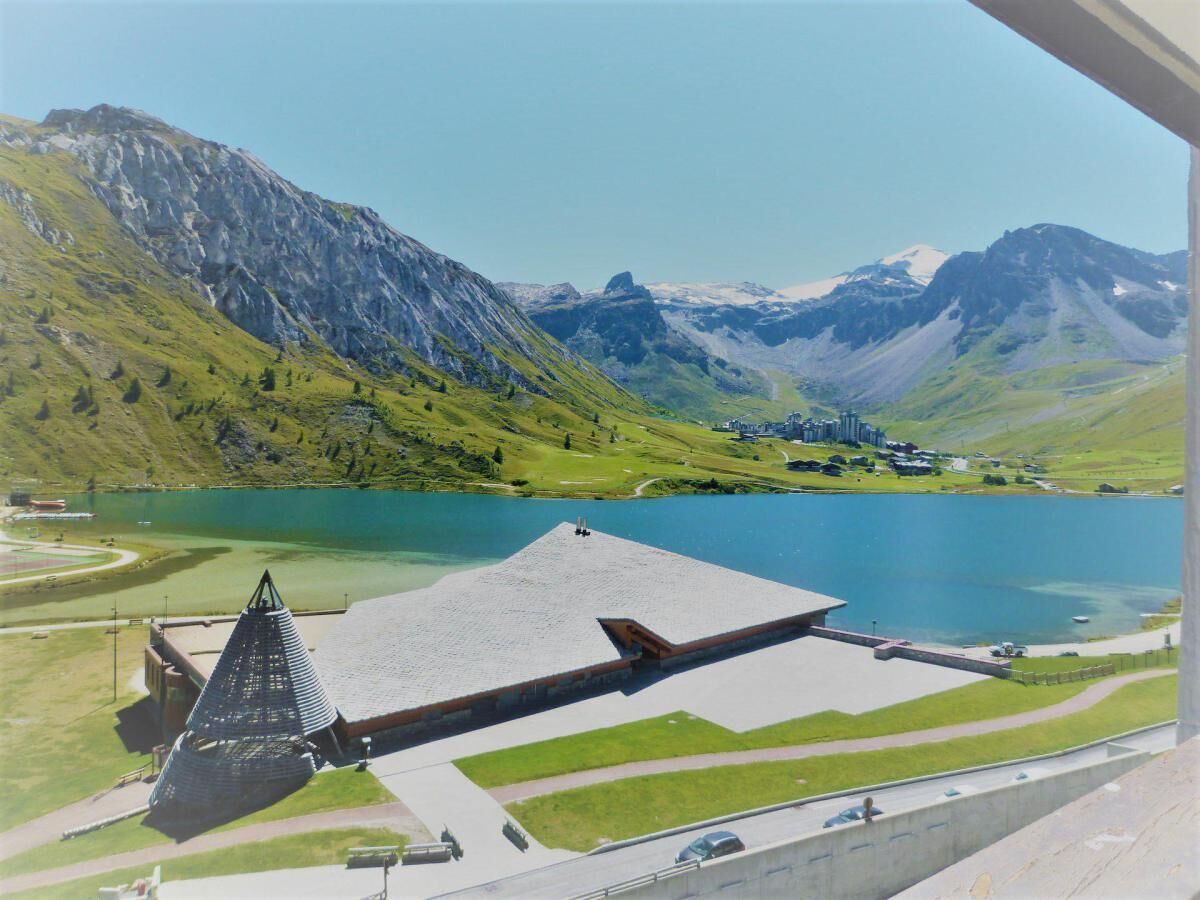 A view of a mountainous landscape with a lake, a building with a triangular roof, and a road.