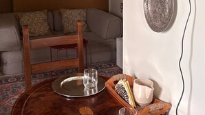 A dining table with a tray, a candle, and a cup. There is a sofa and a lamp in the background.
