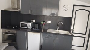 A compact kitchen with a microwave, stove, oven, sink, and cabinets. - A Casa bianca (Lozzi)
