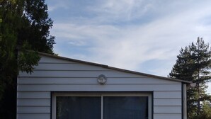 A single-story building with a large garage door, a small circular vent on the roof, and a concrete foundation. - A Casa bianca (Lozzi)
