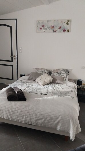 Une chambre Ă coucher avec un lit, des oreillers, une table de chevet, une lampe et une porte.