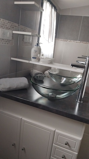 Un baño moderno con un lavamanos de cristal, una toalla blanca y un dispensador de jabón Dove.