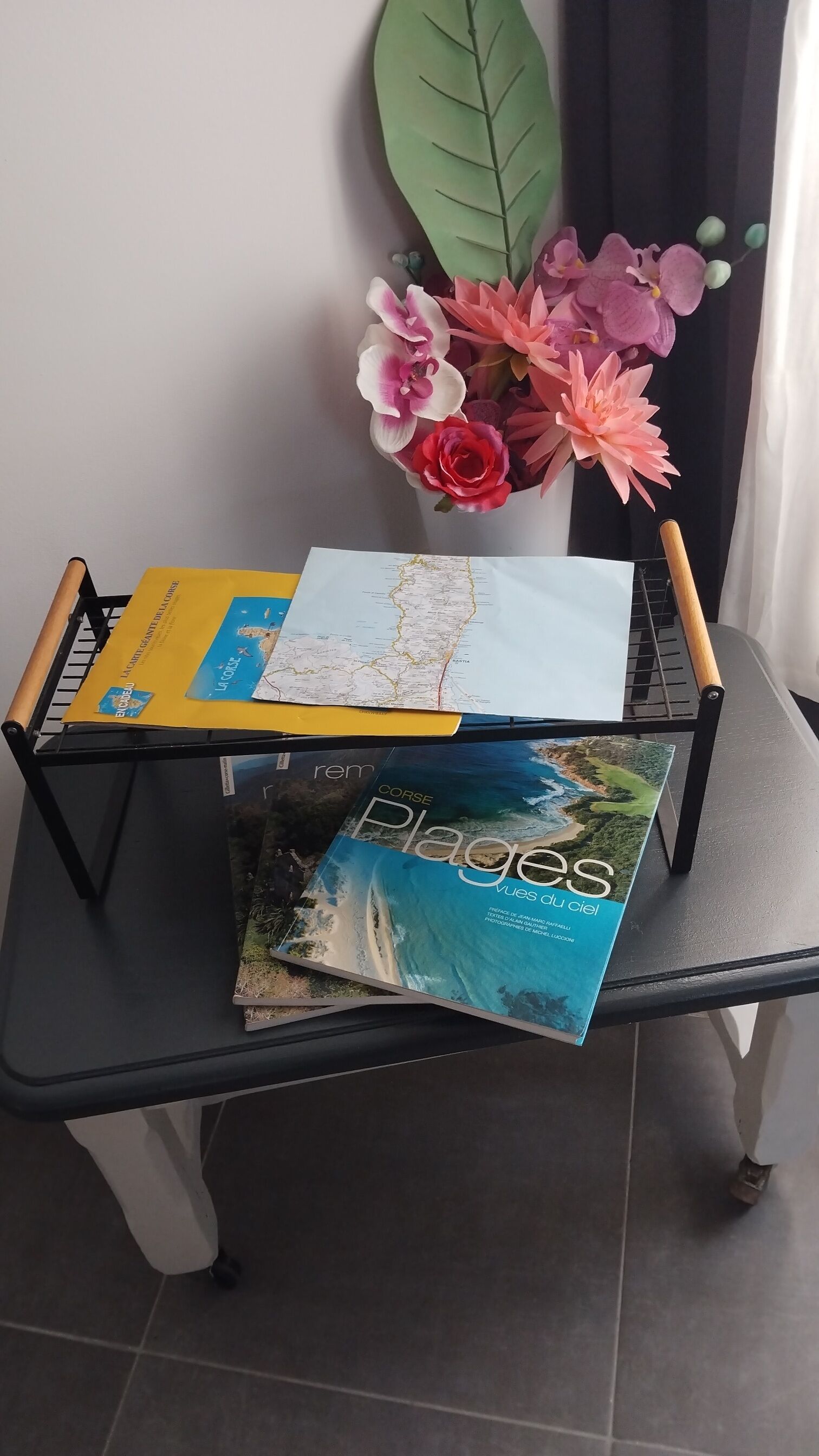 Ein schwarzes Metallregal mit einer Karte und einem Buch mit dem Titel 'Plages'.