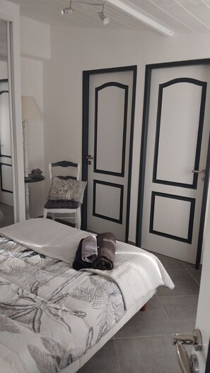 Une chambre à coucher avec un lit, une chaise, une table et deux portes.