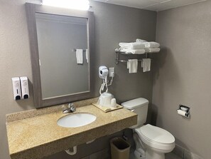 Casa de banho com lavatório bancada de granito, espelho, secador de cabelo, toalheiro e sanita.