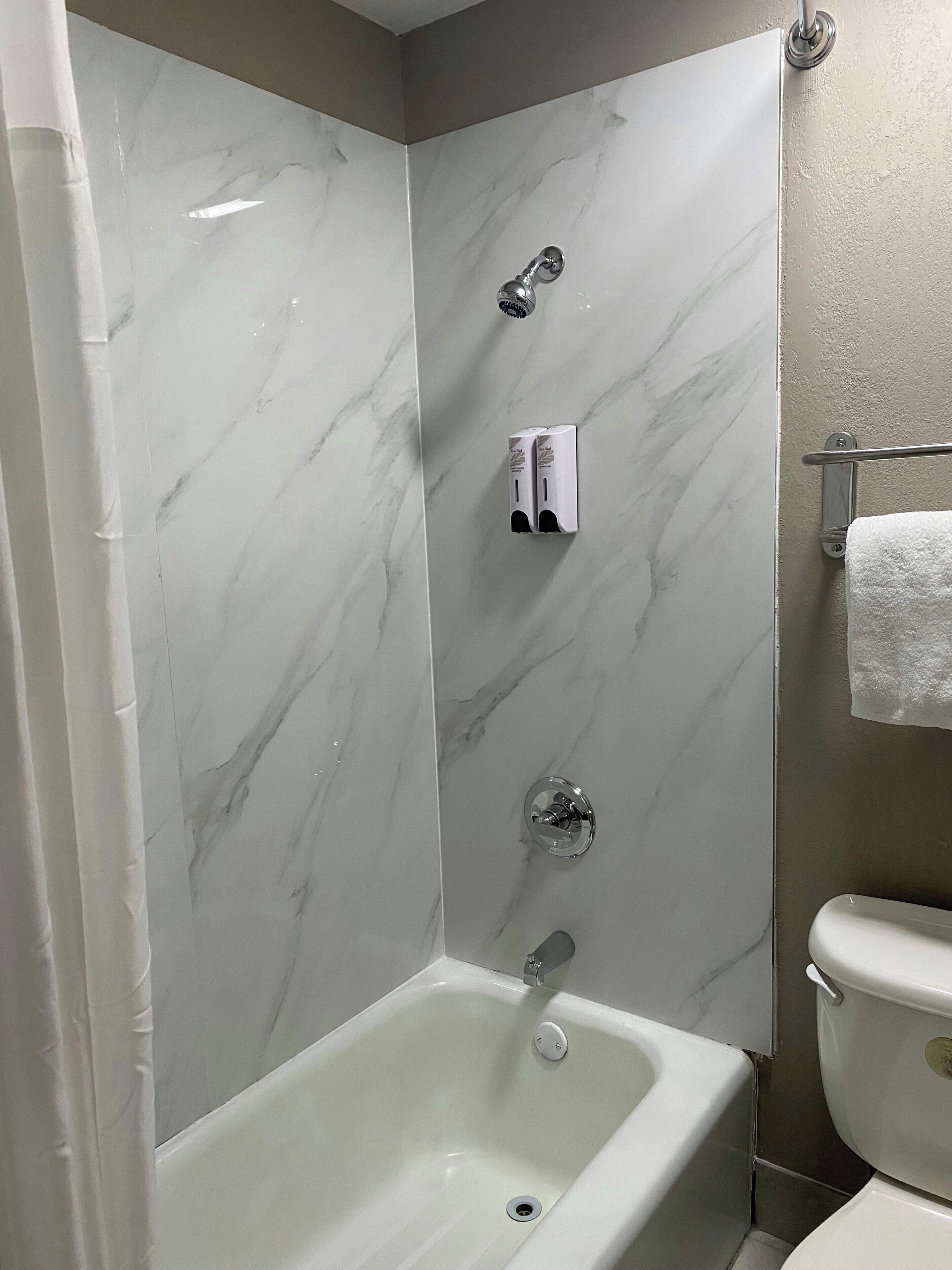 A bathroom with a bathtub, a toilet, and a shower area.