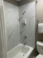 Un baño con bañera, inodoro y zona de ducha.