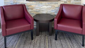 Two red chairs and a small round table in a room with a stone wall and a 'Root Inn' sign.