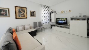 A modern living room with a sofa, chairs, a TV, and a white cabinet. - Real Modern Rapallo Retreat (Rapallo)
