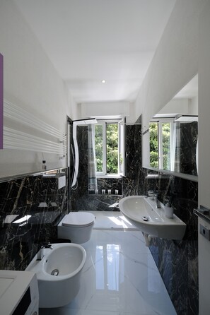 Un bagno moderno con bidet, vasca e uno specchio grande.