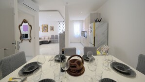 A dining area with a white table set for six, a bottle of wine, and a mirror on the wall. - Real Modern Rapallo Retreat (Rapallo)