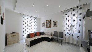 A modern living room with a sectional sofa, a small cabinet, and a TV. - Real Modern Rapallo Retreat (Rapallo)