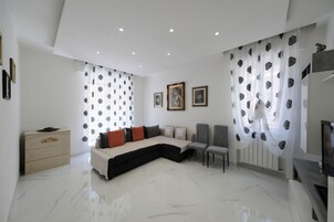 A modern living room with a sectional sofa, a small cabinet, and a TV.
