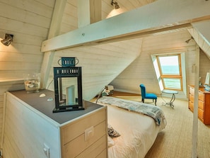 Une chambre à coucher avec un lit, une commode, un miroir, une chaise et une fenêtre donnant sur un beau paysage.