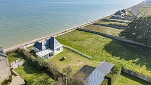 Una propiedad costera con una casa moderna, un espacio con césped y vistas al mar.