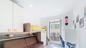 Habitació amb un llit doble superposat, un sofà, un mirall, una porta amb balcó i decoracions murals.