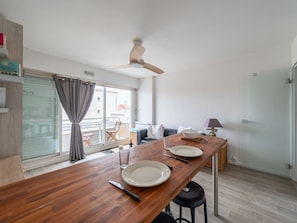 Ein moderner Essbereich mit Holztisch, Stühlen und Deckenventilator.