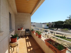 Ein Balkon mit Blumentöpfen, einem kleinen Tisch und einem Stuhl.