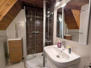 Une salle de bain moderne avec une douche, un lavabo et un meuble-lavabo en bois.