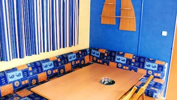 A room with a wooden table, blue patterned bench, and a wall with a geometric wooden decoration.